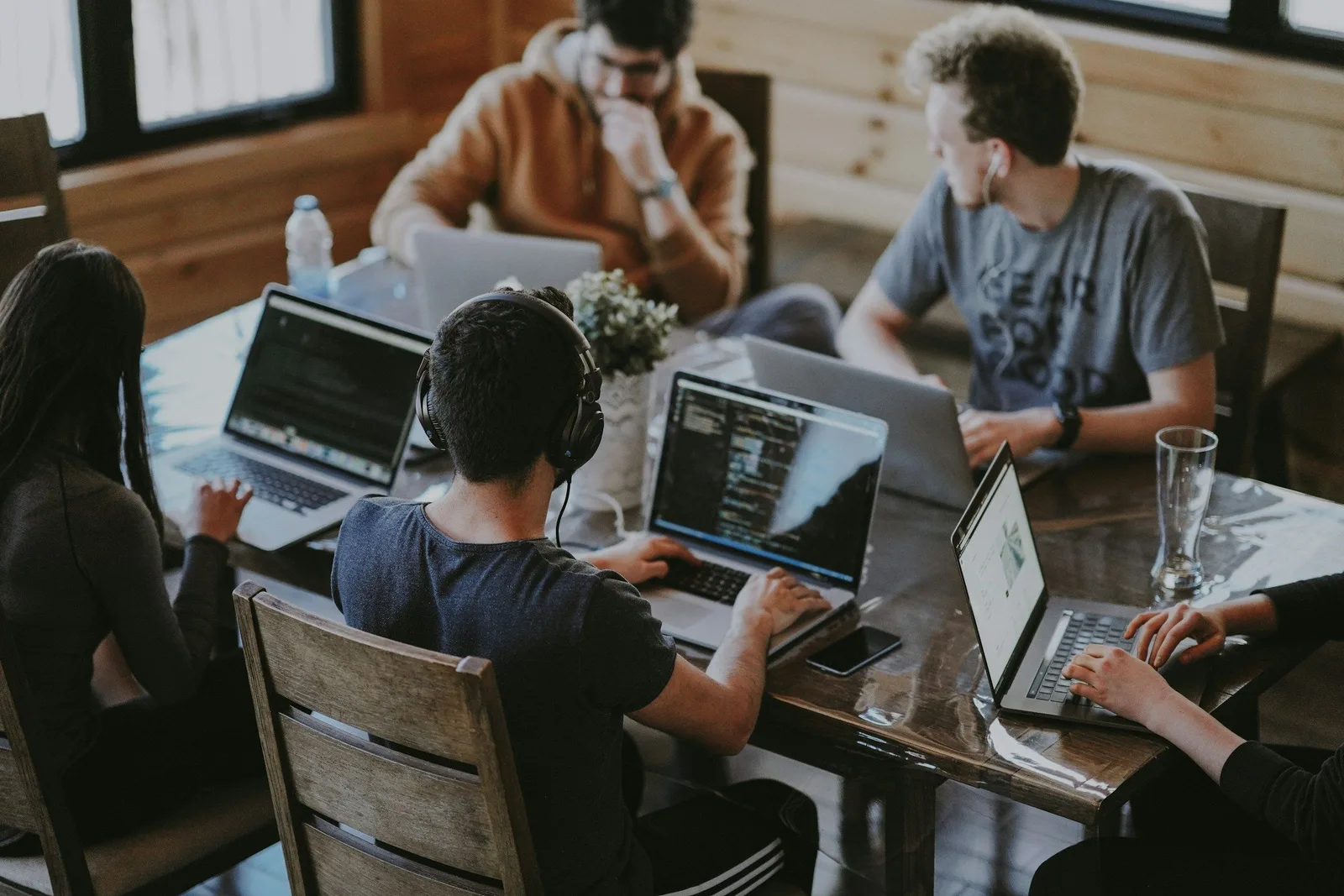 Junges Team arbeitet an einem Tisch gemeinsam an Laptops