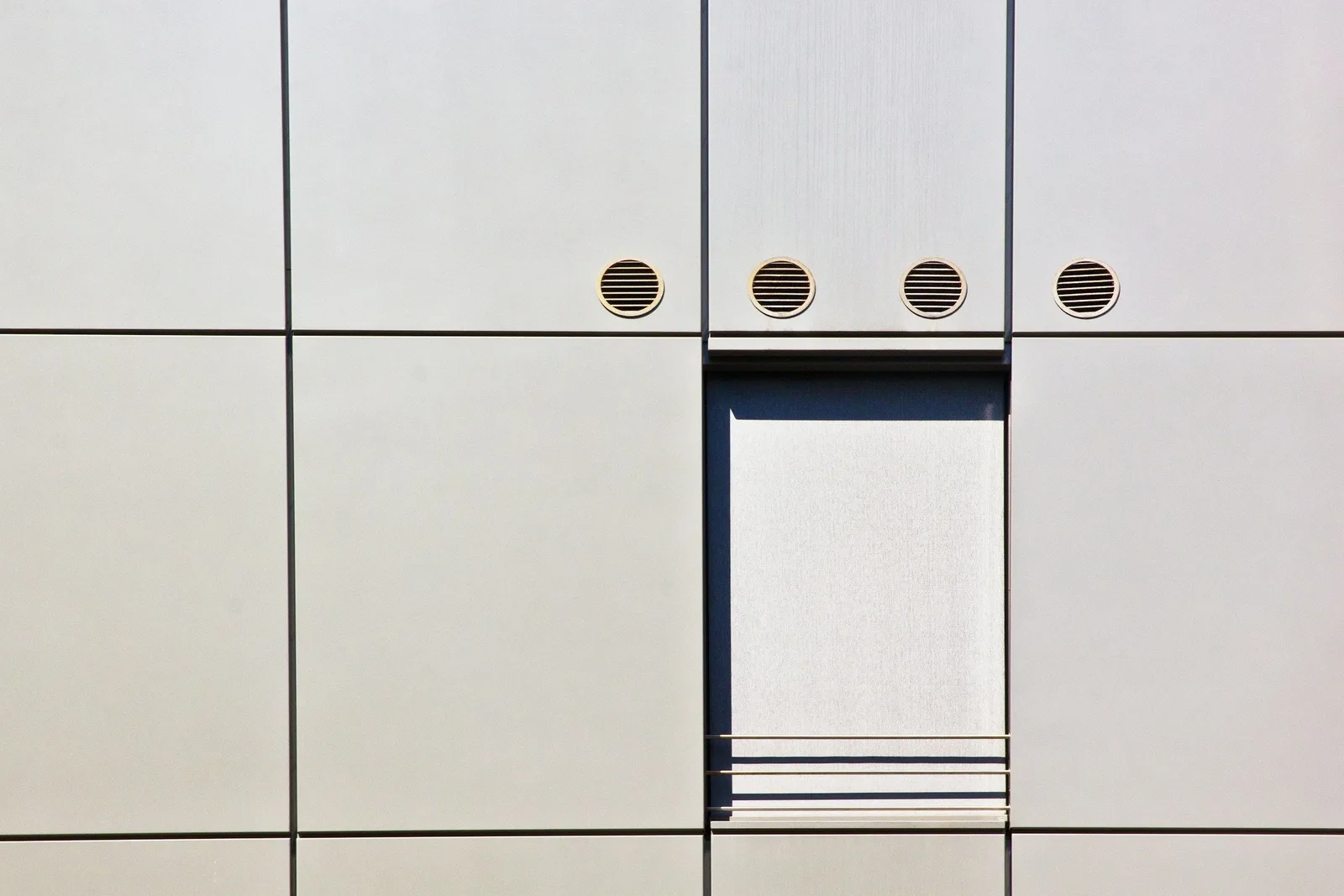 Helle Fassade eines Wohngebäudes mit Fenster und Lüftungsöffnungen